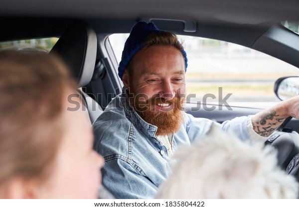 I love my\
dog! Handsome young man driving his car and smiling while looking\
at his white terrier dog. Stock\
photo