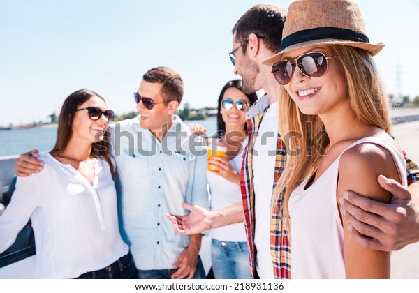 I\
love my friends! Group of young happy people talking to each other\
while beautiful woman looking at camera and\
smiling