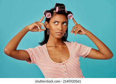 I Love My Hair In Big Bouncy Curls. Shot Of A Young Woman With Rollers In Her Hair Shot Against A Studio Background.