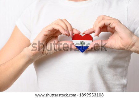 Love Paraguay. The girl holds a heart in the form of the flag of Paraguay on her chest. Paraguayan patriotism concept