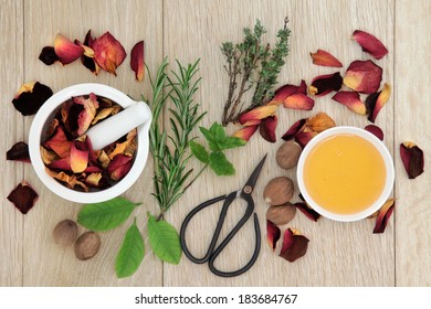 Love Potion Ingredients Of Herb Leaf Sprigs And Rose Flower Over Oak Wood  Background.