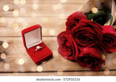 love, proposal, valentines day and holidays concept - close up of gift box with diamond engagement ring and red roses on wood over lights background (vintage effect)