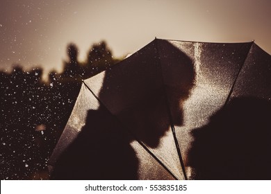 Love in the rain / Silhouette of kissing couple  under umbrella
