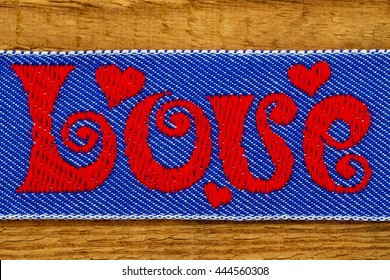 LOVE red word embroidered on denim jeans blue fabric on wooden background, close up - Powered by Shutterstock