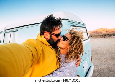 Love and relationship concept with couple of traveler with old vintage van kissing and taking a selfie picture -alternative lifestyle and vacation with beautiful woman and man outdoor enjoying travel - Powered by Shutterstock