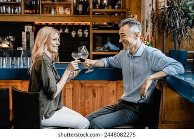 Love and relationship. Happy middle-aged couple drinking sparkling wine cocktails together on a romantic date toasting relaxing at the bar counter in cafe restaurant together. - Powered by Shutterstock