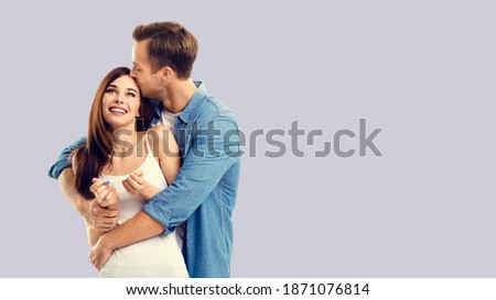 Love, relationship, lovers, family concept - happy couple, finding out results of a pregnancy test. Man kissing woman. Grey background. Copy space for some text.