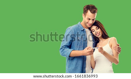 Love, relationship, new parents and happy family concept - young couple, finding out results of a pregnancy test. Green background. Copy space for some text.