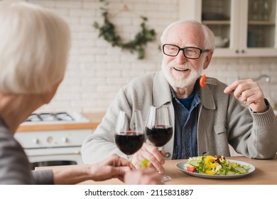 Love And Relationship. Romantic Date At Home. Anniversary Valentine`s Day Birthday Celebration. Happy Old Elderly Senior Couple Grandparents Drinking Wine Having Dinner At Home Kitchen Together