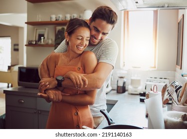 Love, romance and fun couple hugging, cooking in a kitchen and sharing an intimate moment. Romantic boyfriend and girlfriend embracing, enjoying their relationship and being carefree together