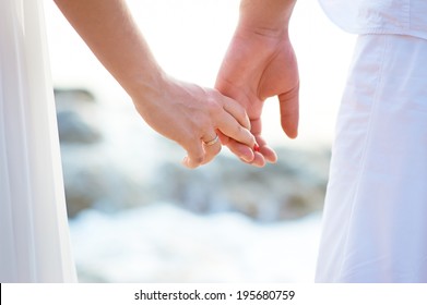 Love - romantic couple holding hands on a beach in sunset.