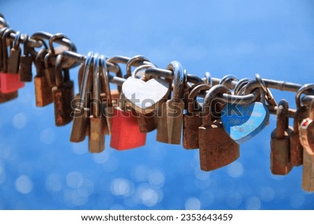 Love, romantic, dating in online internet website. Old rusty love locks on chain against background of blue sea on sunny day. Valentine day love symbol concept. Locked locks of love and loyalty.  