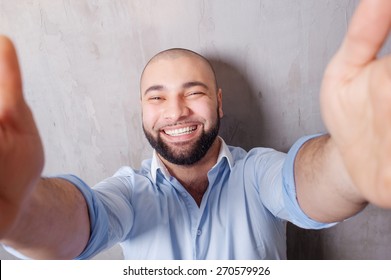 I love selfie! Handsome young latino man in shirt holding camera and making selfie and smiling while standing against grey wall. - Shutterstock ID 270579926