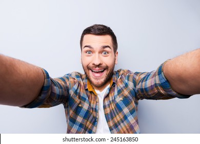 I love selfie! Handsome young man in shirt holding camera and making selfie and smiling while standing against grey background - Shutterstock ID 245163850