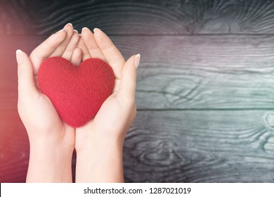 Love Shape Exercise Ball On Female Woman Hand Support On Aging Old Wood Background: Heart Disease Awareness Week: American Heart Month: National Wear Red Day For WomenÃ¢â‚¬â„¢s Heart Health Concept