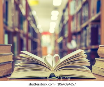 Love story book with open page of literature in heart shape and stack piles of textbooks on reading desk in library, school study room for national library lovers month  and education learning concept - Shutterstock ID 1064324657