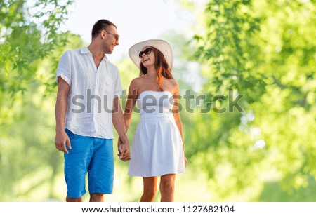 love, summer and relationships concept - happy couple on vacation wearing sunglasses and walking holding hands over green natural background