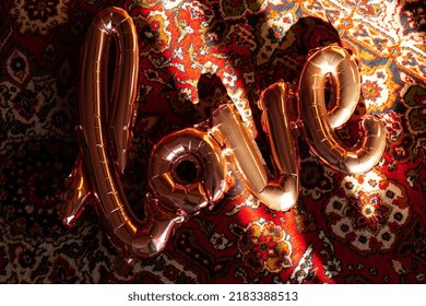 Love text pink foil balloon on authentic Love word from pink inflatable balloon laying carpet. Happy Valentines Day, Mother's Day, birthday concept. Minimalistic creative 