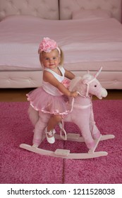I Love This Horse. Small Blond Girl Ride Toy Horse. Small Child Wear Hair Band. Little Girl With Long Hairstyle. Hair Accessory. Toddler Hairstyle For Girls. What A Doll Baby.