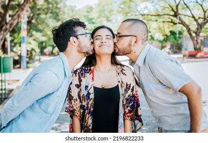Love Triangle Concept. Polygamy Concept. Two Men Kissing A Girl Cheek. Portrait Of Two Guys Kissing A Girl Cheek. Two Young Men Kissing A Woman Cheek Outdoor