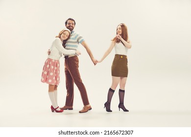 Love Triangle, Intrigue. One Young Man And Two Girl In Vintage Retro Style Outfits Psoing Isolated On White Background. Concept Of Relations, Family, 1960s American Fashion Style And Art.