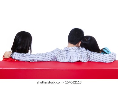 Love triangle of two woman and one man sitting on red sofa. Isolated on white