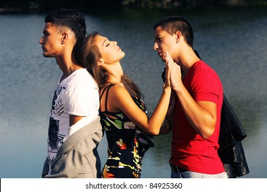 Love Triangle, Two Young Men And Young Woman On The Beach At Sunset