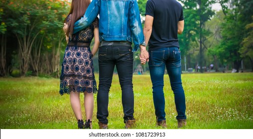 Love triangle. Young woman in relationship with two men.back view of threesome love friends of two men and one woman.