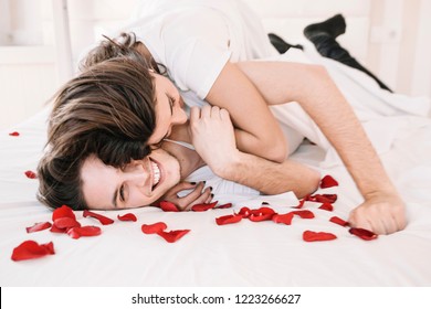 Love Valentine Day Couple Lying In Bed, Man Giving A Rose, Greeting Card To His Beautiful Wife In Bed, Happy Smile Looking To Each Other