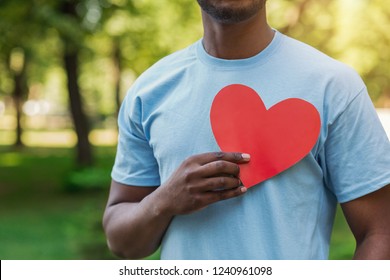 Love, volunteering and charity concept, copy space. Young black man holding red heart on his chest. - Shutterstock ID 1240961098