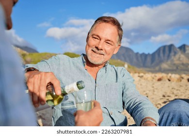 Love, wine and happy with old couple on beach for celebration, anniversary and romantic date. Smile, relax and sunset with man pouring champagne for woman for vacation, summer break or travel holiday - Powered by Shutterstock