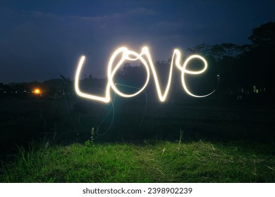 Love word curves light painting in the field at night. Love for nature