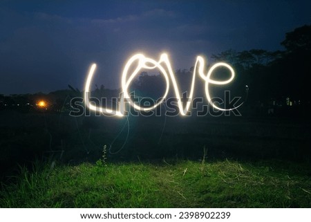 Love word curves light painting in the field at night. Love for nature