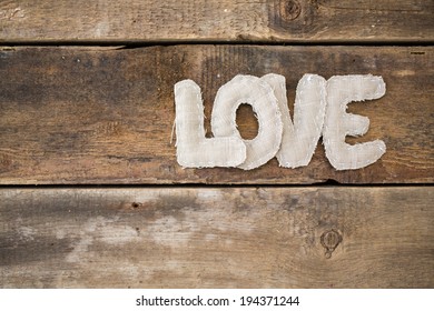 Love word from fabric on grunge old wooden background