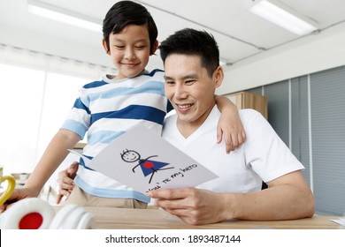 I Love You, Dad. Asian Happy Family Son Surprise, Made A Greeting Card My Hero For Daddy On Father's Day. Conecept Warm Love Bond