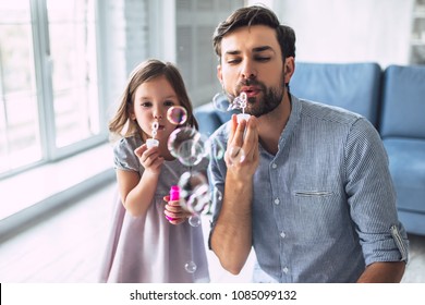 I love you, dad! Handsome young man at home with his little cute girl are having fun and blowing soap bubbles. Happy Father's Day! - Powered by Shutterstock