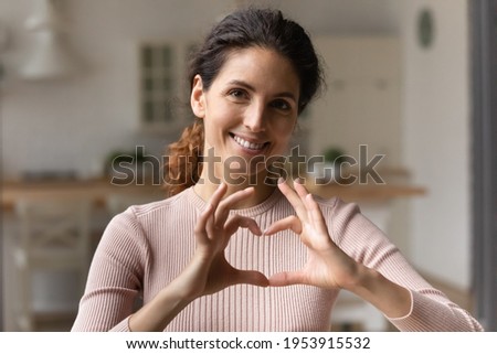 I love you. Grateful loving young latina female posing for portrait hold heart of united fingers close to breast. Happy hispanic woman look at camera show like gesture express gratitude appreciation