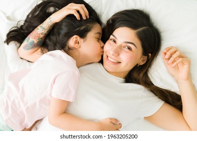 I Love You, Mother. Young Mom Making Eye Contact And Smiling While Hugging Her Adorable Daughter In Bed