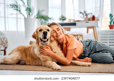 Love for your pet. A golden retriever lies on the floor in the gentle arms of his loving owner. A happy woman with closed eyes shows tenderness and care for a dog. - Powered by Shutterstock