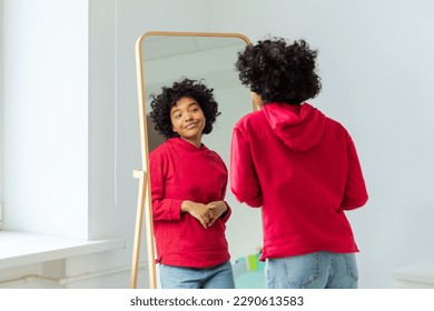 Love yourself. Beautiful young smiling african american woman dancing enjoying her mirror reflection. Black lady looking at mirror looking confident and happy. Self love concept