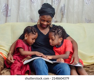 Lovely African Nigerian Family Consisting Of A Mother Or Guardian And Two Little Girl Child, Sitting Curdled Together As They Happily Study Altogether