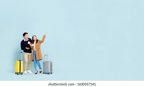 Lovely Asian Couple Tourists With Baggage  About To Go For Winter Honeymoon Travel Isolated On Light Blue Background With Copy Space