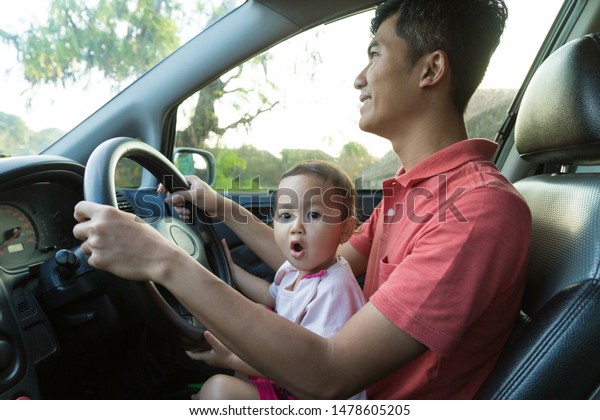 lovely asian daughter with father in the car\
playing together