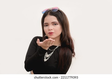 A Lovely Asian Woman Shows A Romantic Gesture Of Blowing A Kiss To The Camera Or A Studio Photo With Plain White Background.