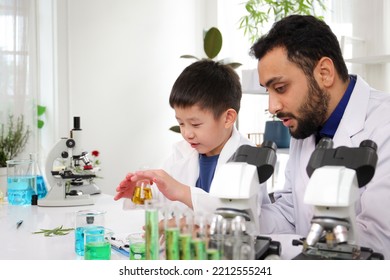 Lovely Asian Young Boy In Lab Coat Enjoy Doing An Experiment And Studying A Science. Smart Asian Little Boy Learning A Science Experimental With Expertise Scientist Or Science Researcher In Laboratory