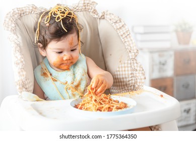 Lovely Baby Girl Eating Spaghetti And Making A Mess. Family Leave Baby Alone, Eating Pasta Herself.