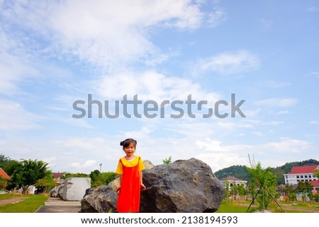 Lovely Baby girl wears yellow-orange outfit (gokowa outfit) in a public park. Girls and teen fashion dress.