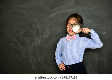 lovely beautiful little girl children standing in chalkboard background and using magnifier magnifying looking at camera. - Powered by Shutterstock