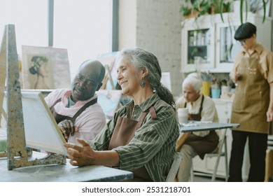 Lovely biracial senior couple admiring painting together during art therapy attendance - Powered by Shutterstock