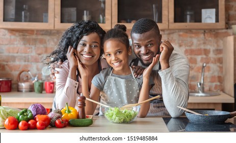 Lovely Black Family Cooking Healthy Dinner Together At Kitchen, Posing At Camera, Making Salad, Panorama With Copy Space